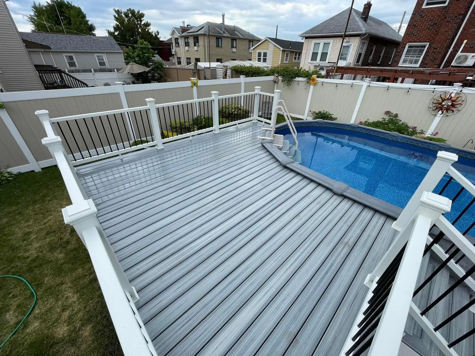 Above-ground pool deck with gray composite decking and white railings