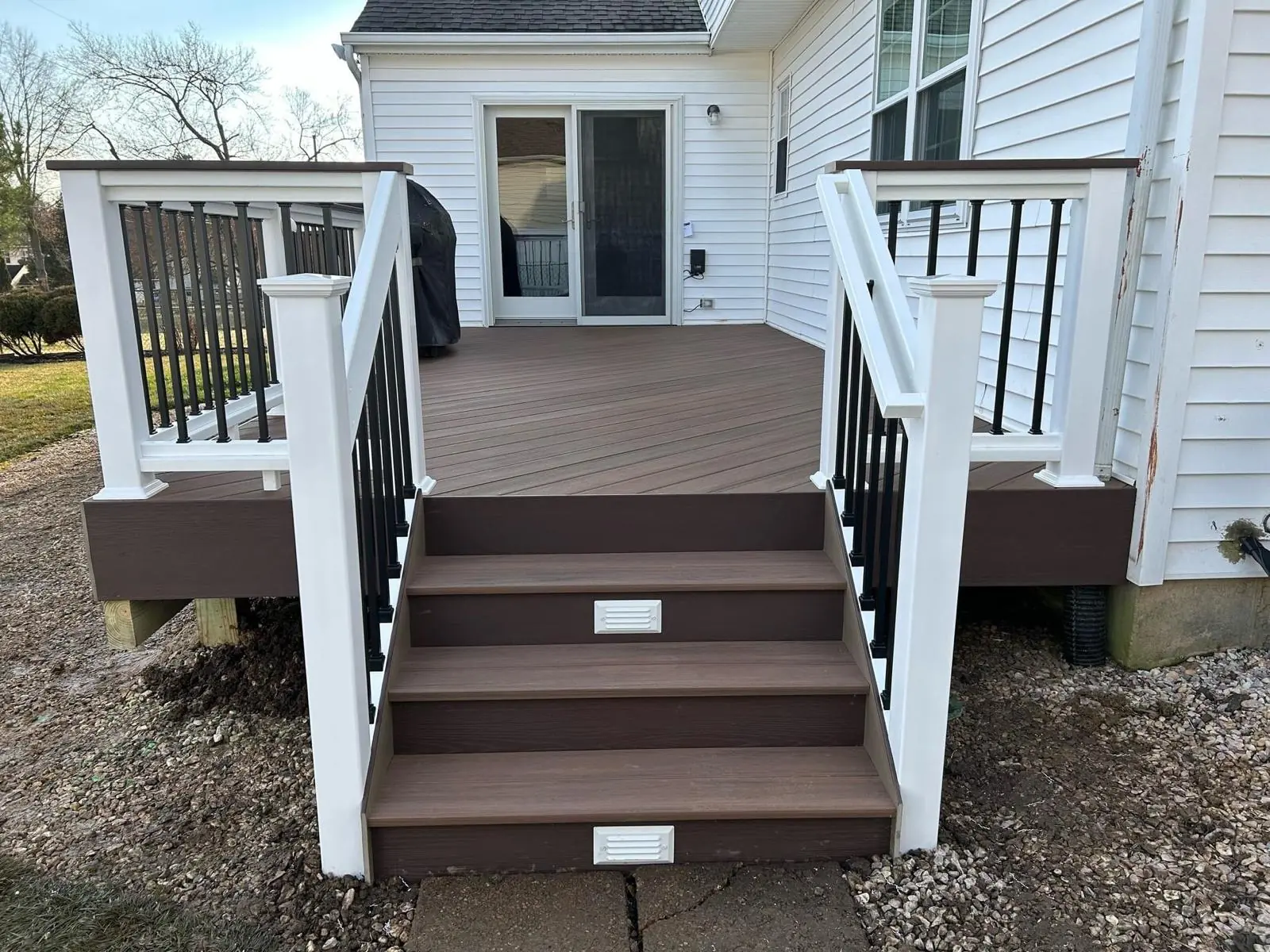 Composite deck built by ProDecks Delaware with white railings and steps